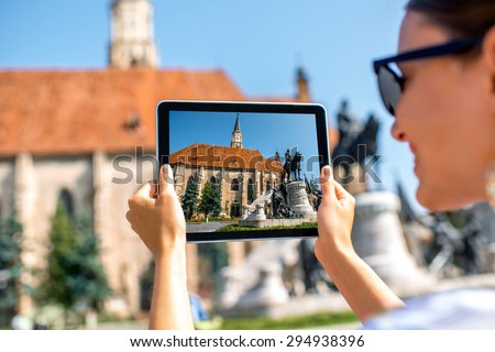 Female tourist photographing with digital tabet Michael\'s church in Cluj Napoca. Traveling Romania