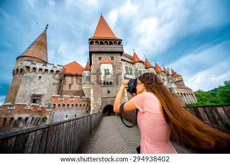 Female tourist photographing with professional photo camera Corvin castle. Tourism in Romania, European country.