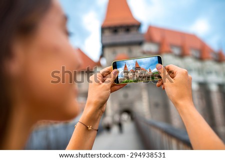 Female tourist photographing with smart phone Corvin castle. Tourism in Romania, European country.
