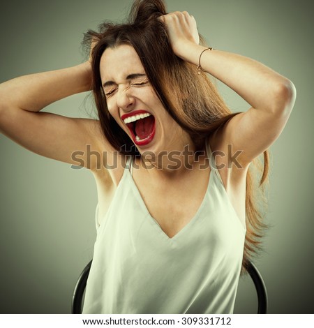 Studio portrait of young yelling woman on grey background. Photo with cross processing filter
