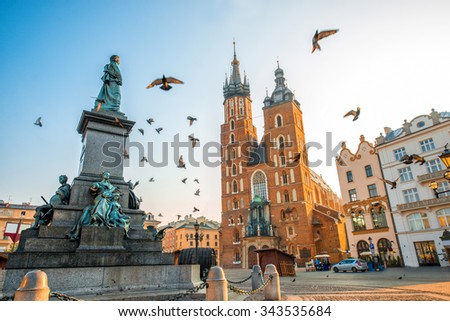 Old city center view with Adam Mickiewicz monument, St. Mary\'s Basilica and birds flying in Krakow on the morning