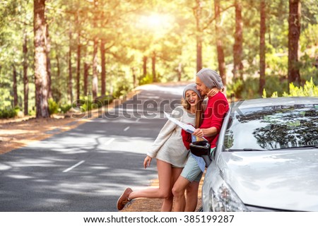 Young family in sweaters and hats holding paper map traveling La Palma island by rented car in the forest
