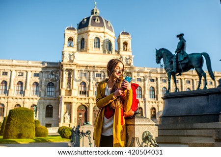 Young female tourist with smart phone on Maria Theresa square near museum of Natural history in Vienna.