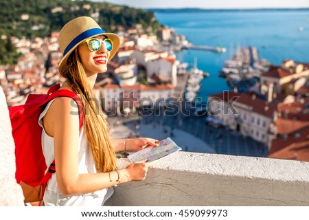 Young female traveler with red backpack and hat enjoying the view from George\'s tower on Piran old town. Traveling in Slovenia