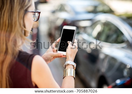 Woman holding a smart phone with empty screen to copy paste with electric car charging on the background