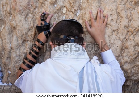 jewish teenager celebrate bar mitzvah at the wailing wall and praying with hands on the stones