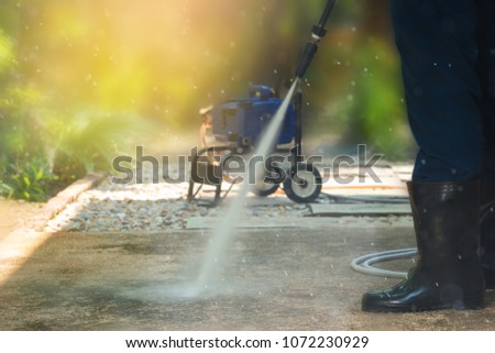 Man cleaning dirty walkway with high pressure water cleaner ,professional cleaning services concept.\
High pressure cleaning, side view.