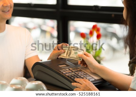 Pay bill at vintage coffee shop with cash.\
Young customer and cashier holding money  with smiling face