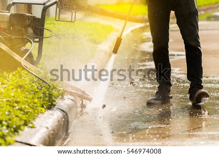 High pressure deep cleaning\
Worker cleaning driveway with gasoline high pressure washer,sunlight background.