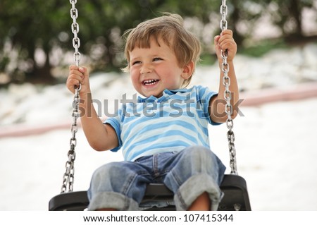 Little cute boy having fun on chain swings.