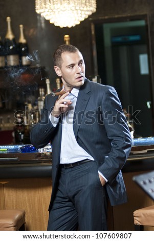 Businessman smoking cigar next to bar stand.
