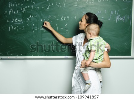 Yang mom with baby boy is writing down formulas in the class board.