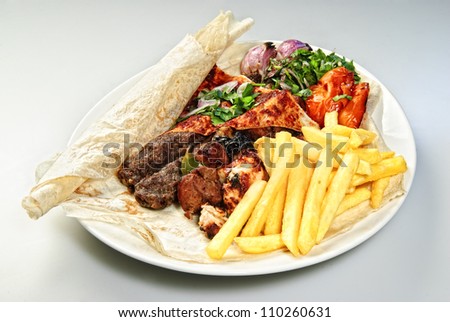 Plate of Arabic french fries with roasted meat and vegetables.