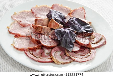 Plate of multiple meat cuts topped with spinach leafs.