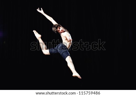 Modern ballet style dancer jumps on black background