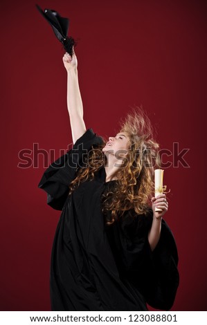 Studio portrait of beautiful curly female graduating student dressed in cup and gown.