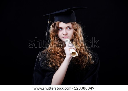 Studio portrait of beautiful curly female graduating student dressed in cup and gown.