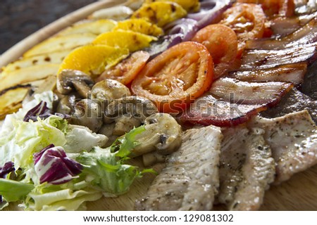 Plate of different kinds grilled  meat with fruits and vegetables.