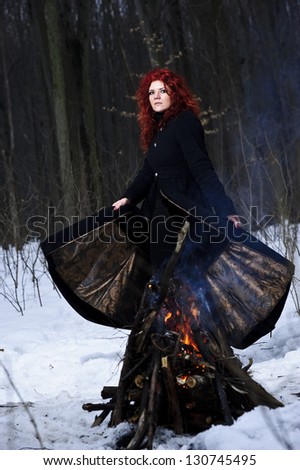Portrait of red haired beautiful and wild yang woman the hunter in the winter gloomy forest.