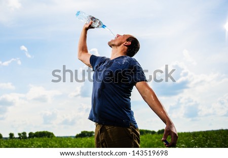 Adult mam plays with water among green field.
