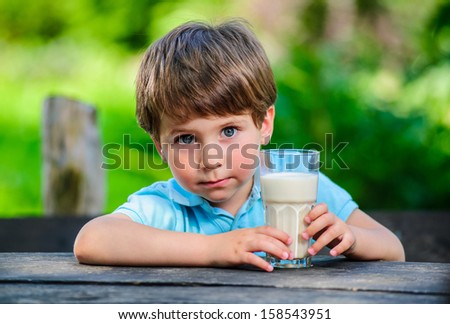 Yang little and cute boy pictured with glass of milk.