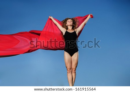 Professional gymnast woman dancer posing in front of sunset sky and red fabric background