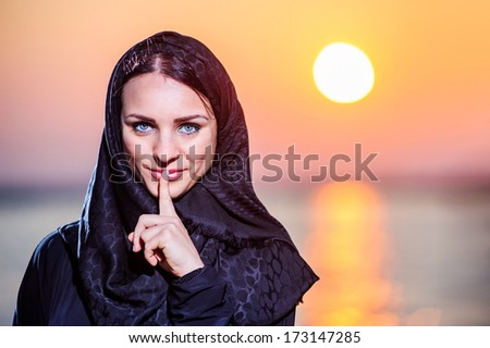Women dressed middle eastern way poses on sunset background.