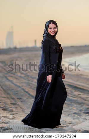 Women dressed middle eastern way poses on sunset background.