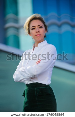 Yang and beautiful modern business woman poses outdoor in urban background.