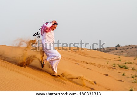 Middle eastern way dressed Arabic man poses in the desert sunset time.
