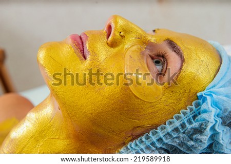 Beautiful woman with facial golden mask at beauty salon.