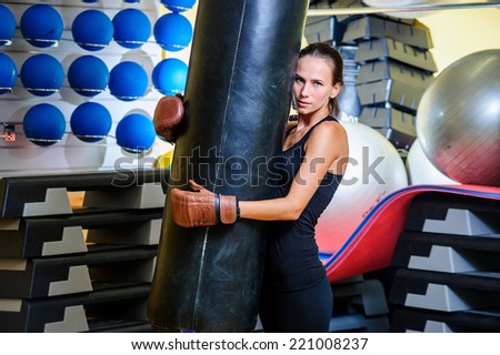 Beautiful sporty woman boxing with red punching bag at gym.