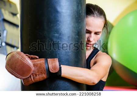 Beautiful sporty woman boxing with red punching bag at gym.