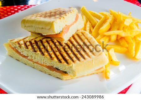 Grilled club sandwich with french fries isolated on white plate.