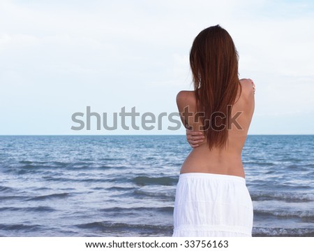 Lonely and sad young lady standing at the sea