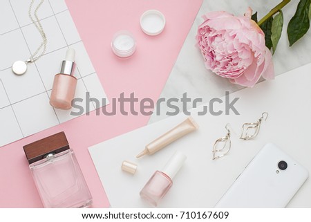 Beauty flat lay with cosmetic bottles, phone and flower. Top view