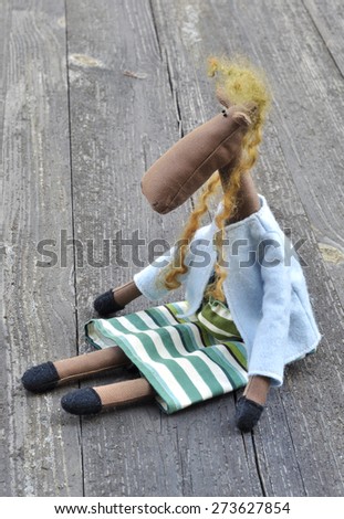 The toys are hand made. Doll Tilda. Sad horse is sitting on a wooden Board.