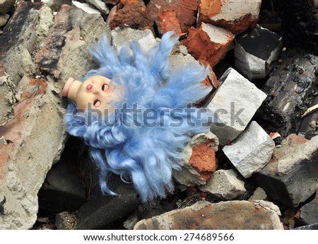 doll\'s head amid the debris of destroyed houses