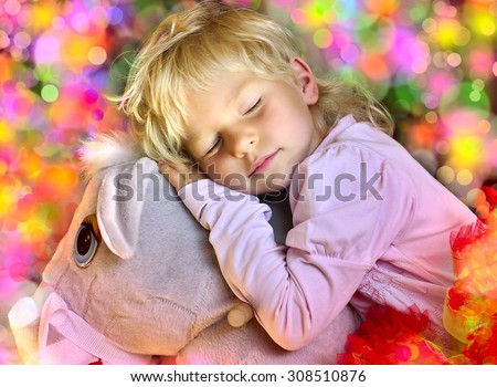 The little Girl fell asleep on a toy horse and sees a happy sleep.