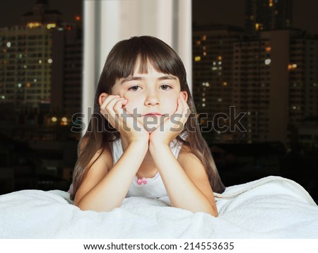 Portrait of caucasian sad girl child kid on background of window with night town