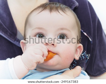 Portrait of little caucasian baby boy eating dried apricot
