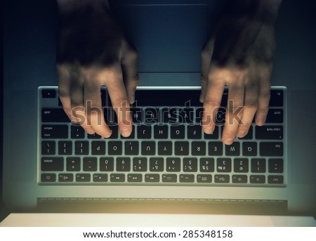 hands with laptop above typing in night