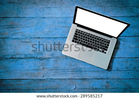 laptop with white blank screen on wooden blue boards as texture with copyspace