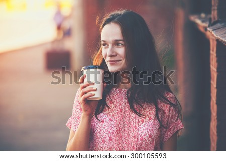 smiling pretty girl walking in street with morning coffee
