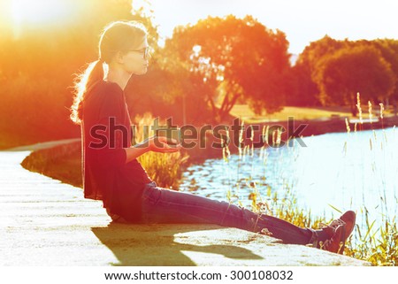 Smiling girl with cup of tea or coffee enjoying on summer shore of river