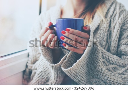 hands holding hot cup of coffee or tea in morning