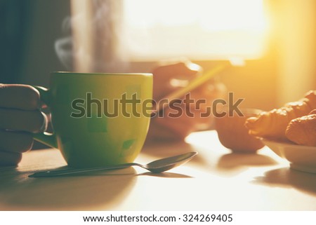 fresh breakfast with hot coffee and browsing smartphone in morning sunlight