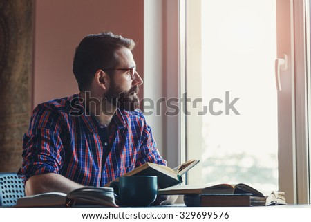 Bearded man reading books at table
