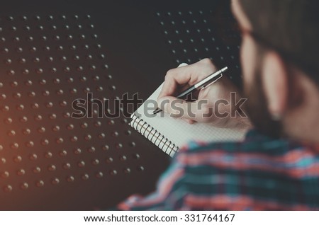 bearded man writing with pen in notebook