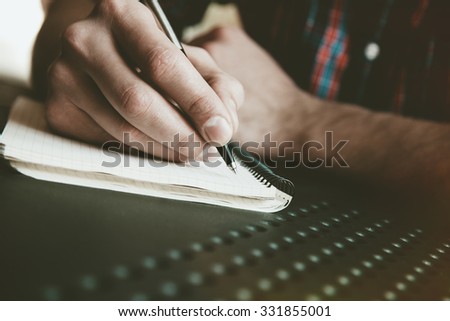 male hand writing in notebook with pen